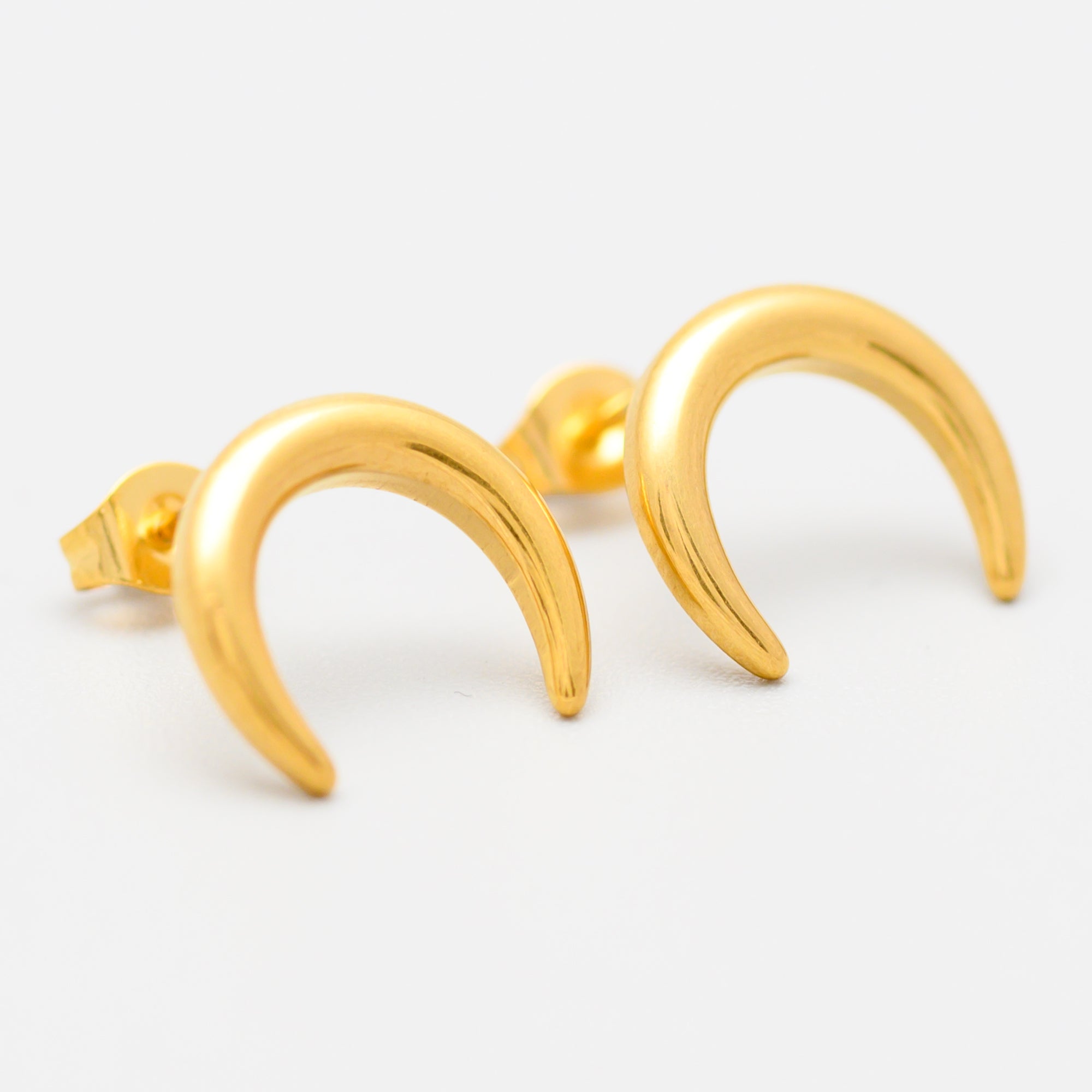 Gold crescent moon-shaped earrings on a white background