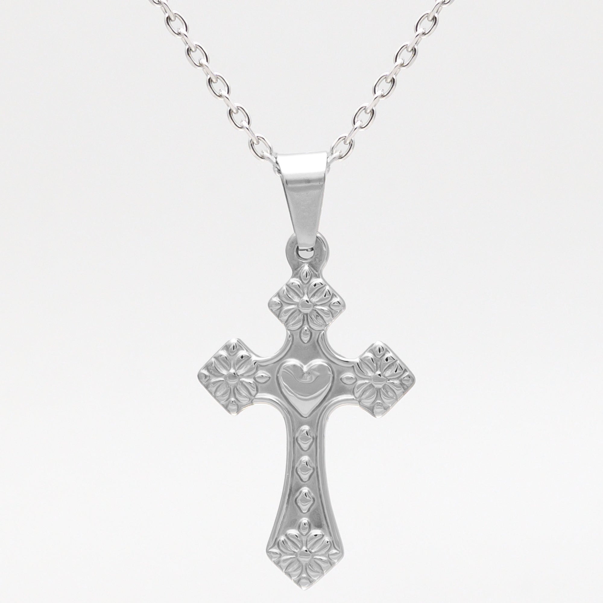 silver cross with heart shaped design on a cable chain necklace