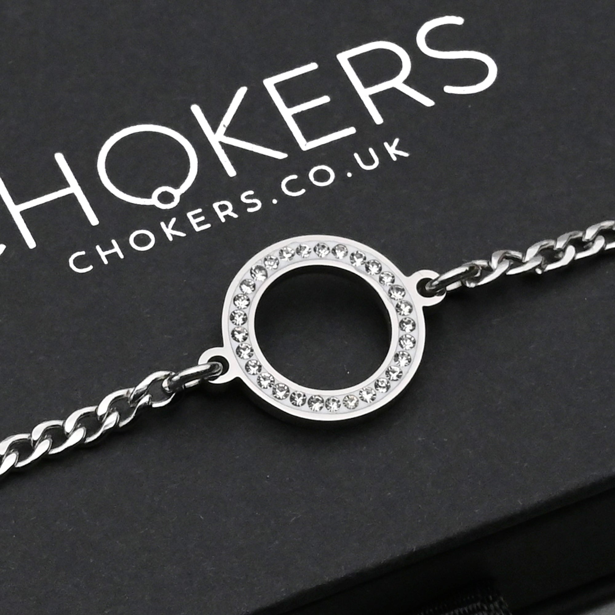 Close up of a Small gemstone set O ring day collar on a dainty cuban style chain