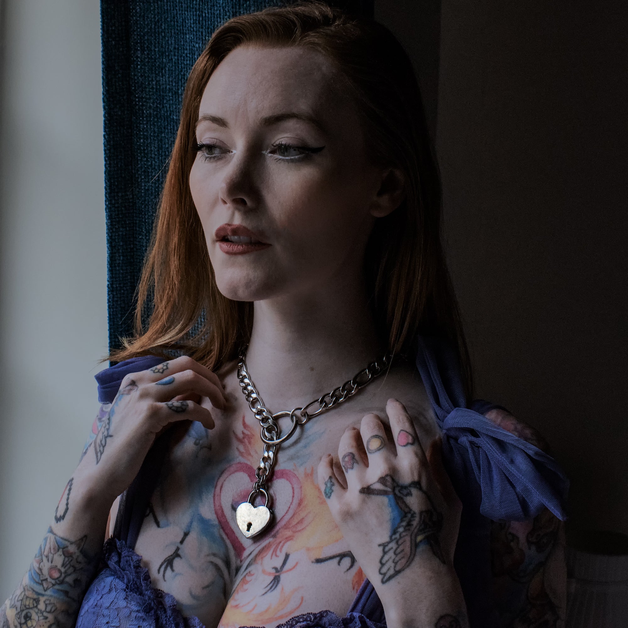 Model wears silver coloured figaro style slip chain choker with heart shaped padlock