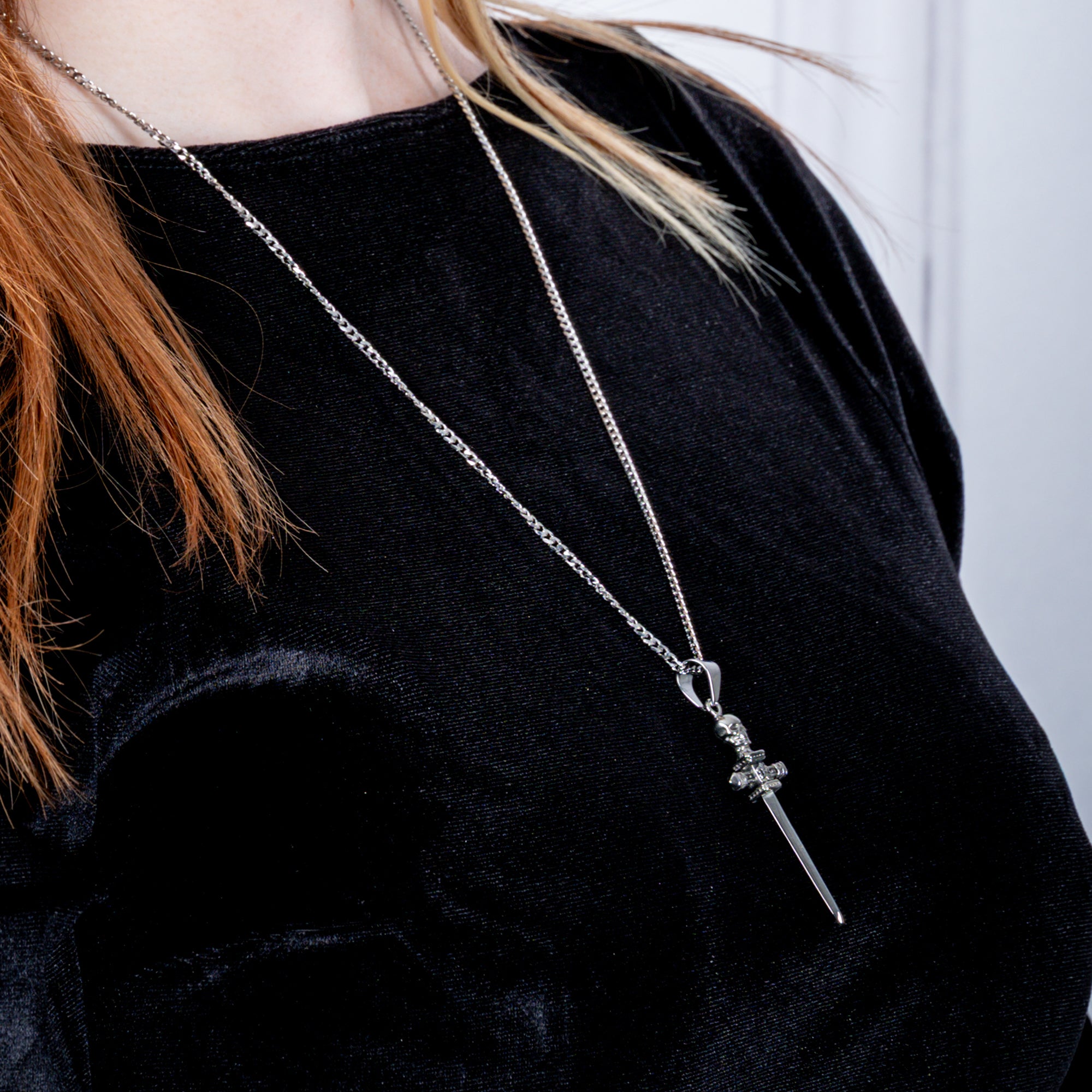 Sword pendant featuring a skull and fleur de lis symbol on the handle on a dainty 3mm cuban link chain necklace
