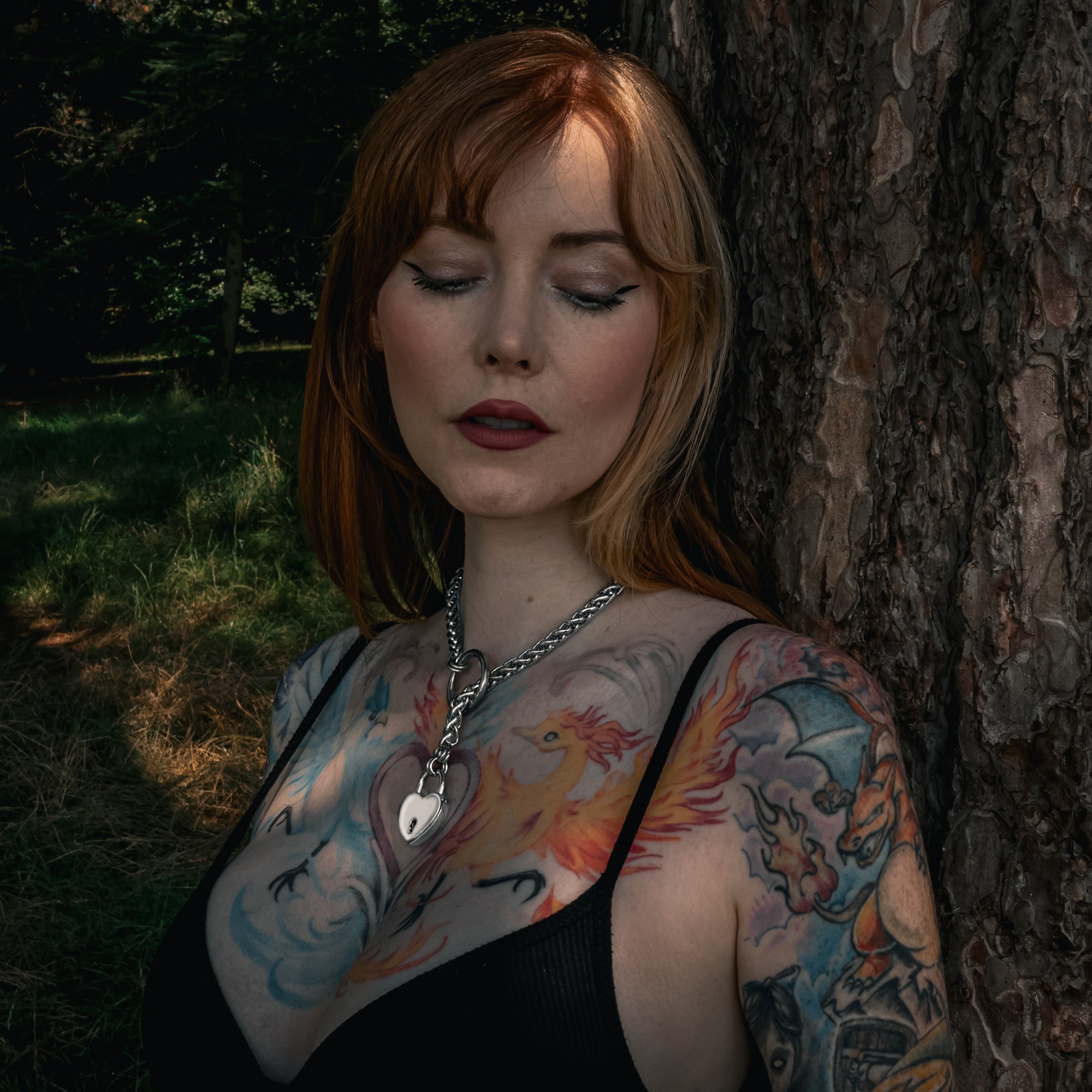 Close up of silver coloured chunky foxtail slip chain choker & heart padlock in a woodland setting