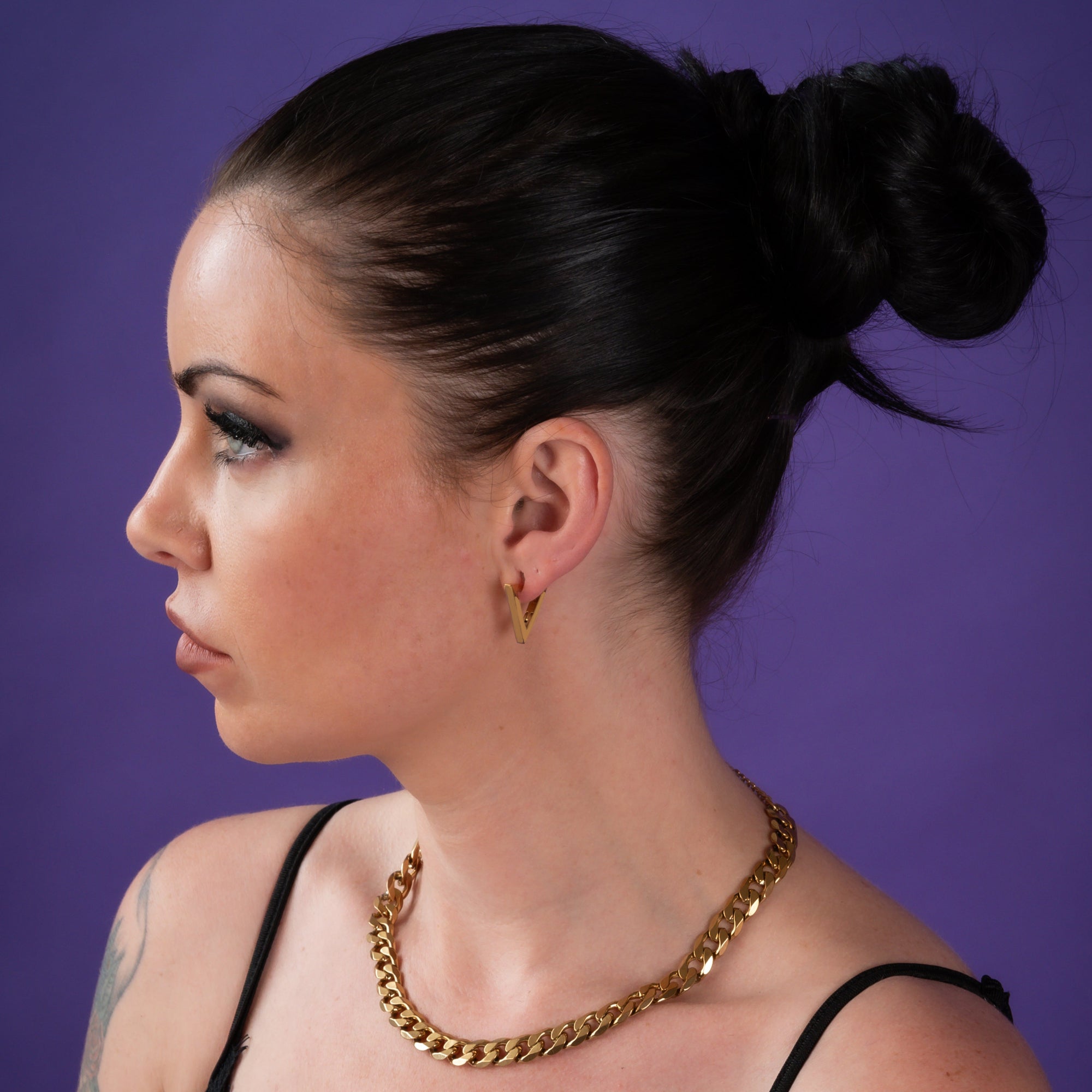 Woman wearing gold triangle earrings with chunky gold cuban necklace
