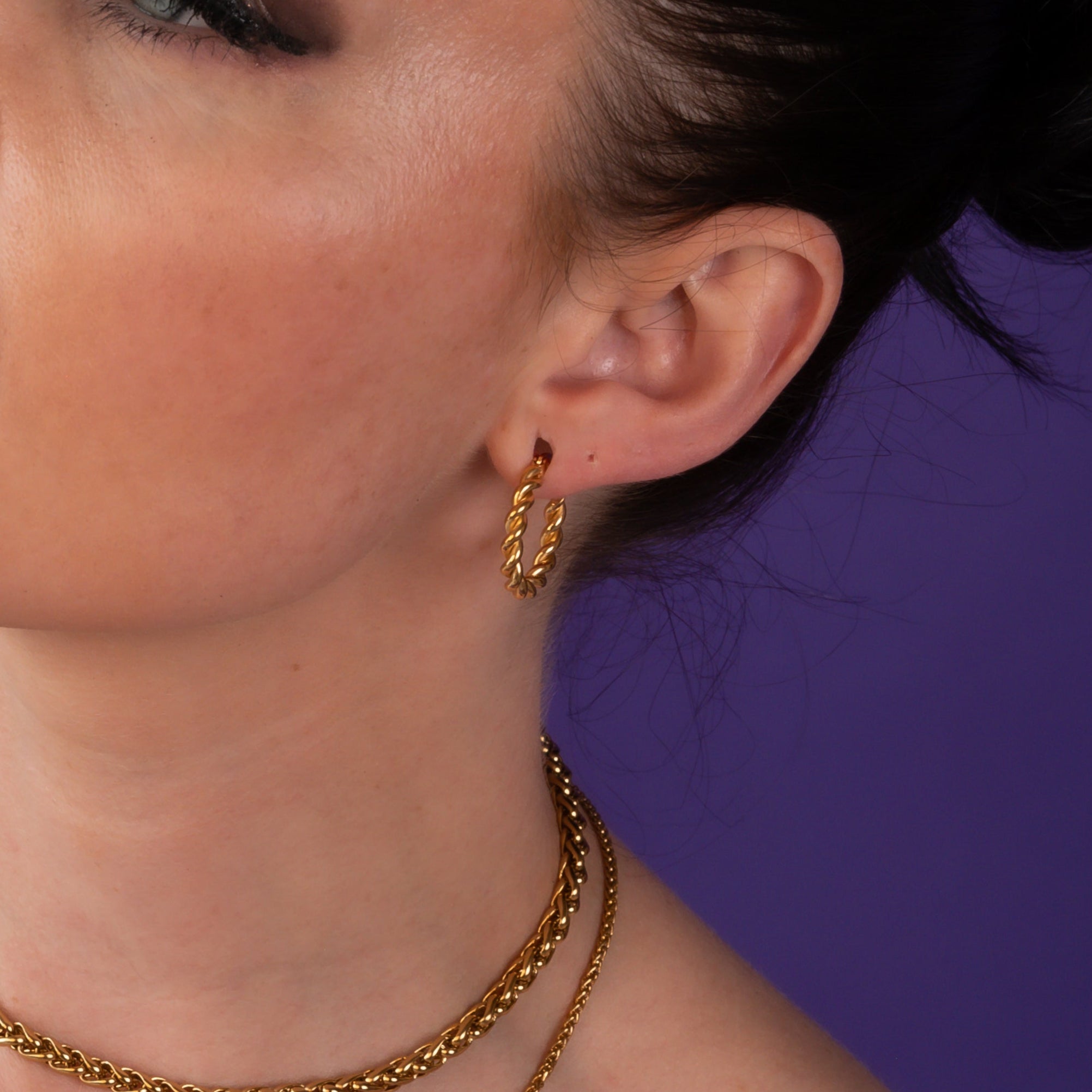 Woman wearing large twisted gold hoop earrings