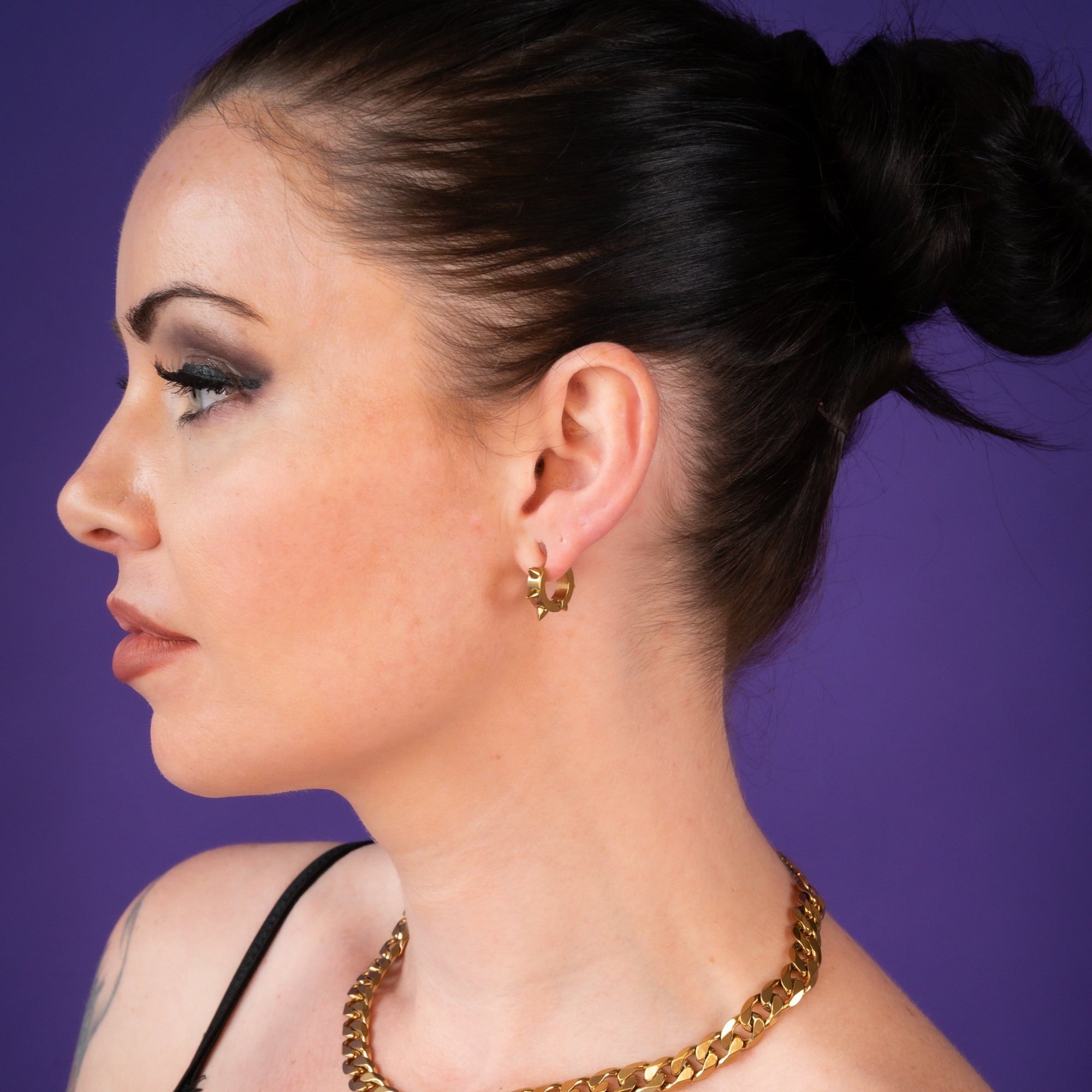 Gold spiky hoop earring worn by a woman