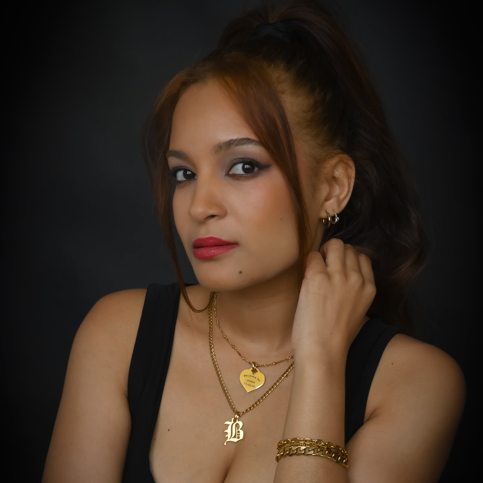 Woman wearing gold jewelry against a dark background