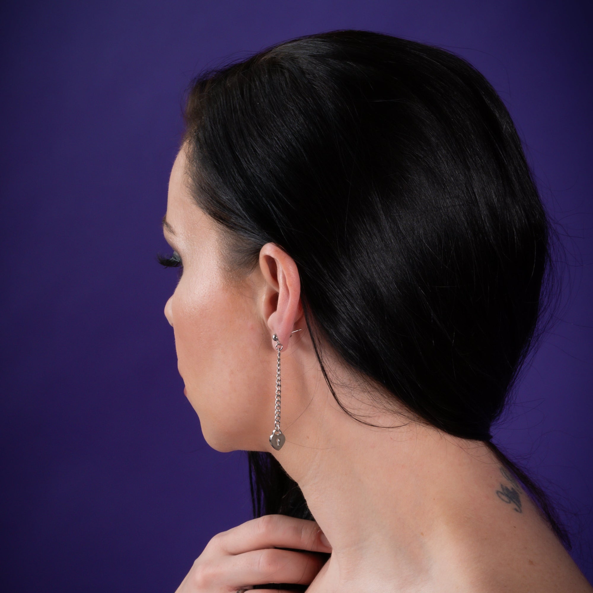 Woman wears heart padlock drop earrings in silver