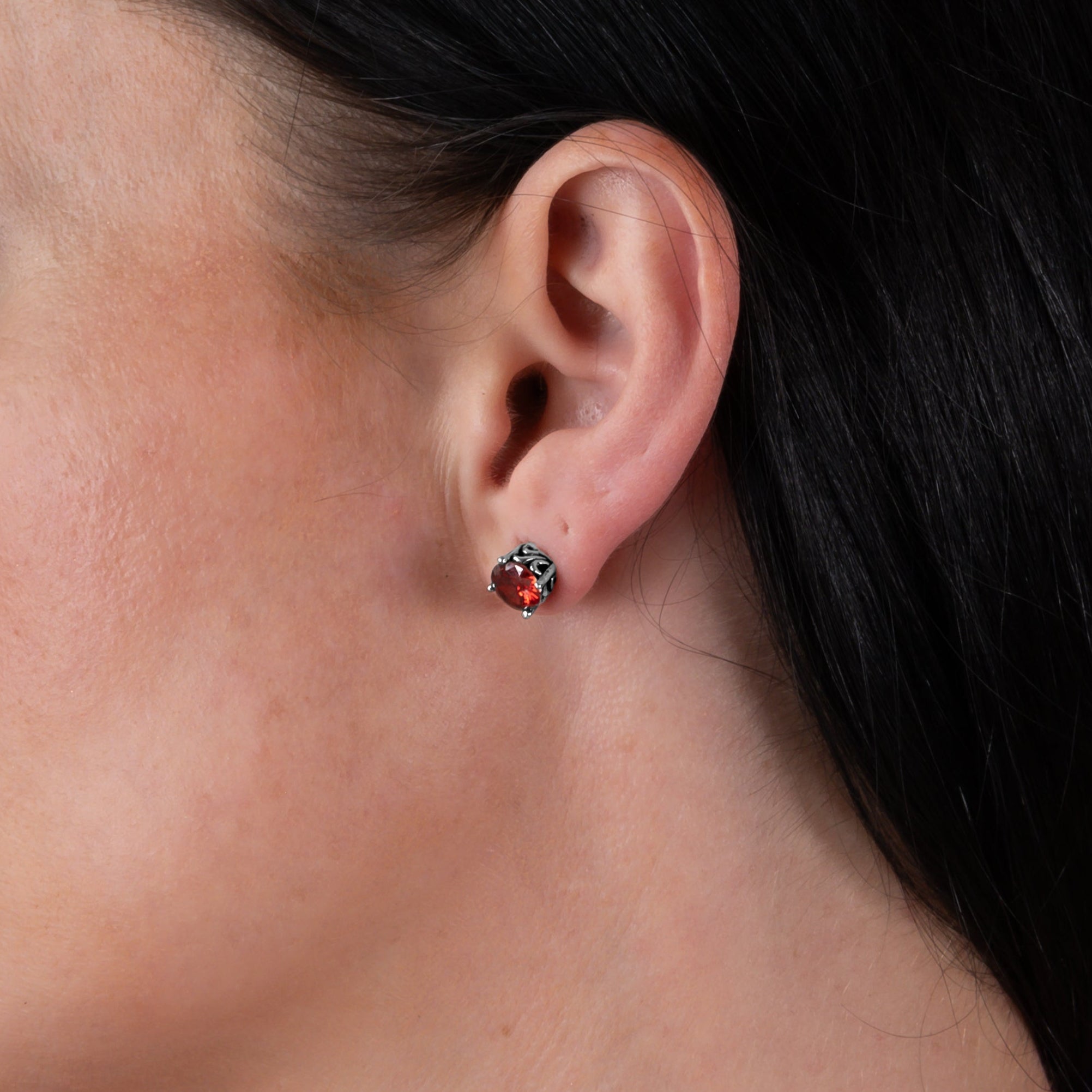 Woman wears ruby red silver gothic stud earrings