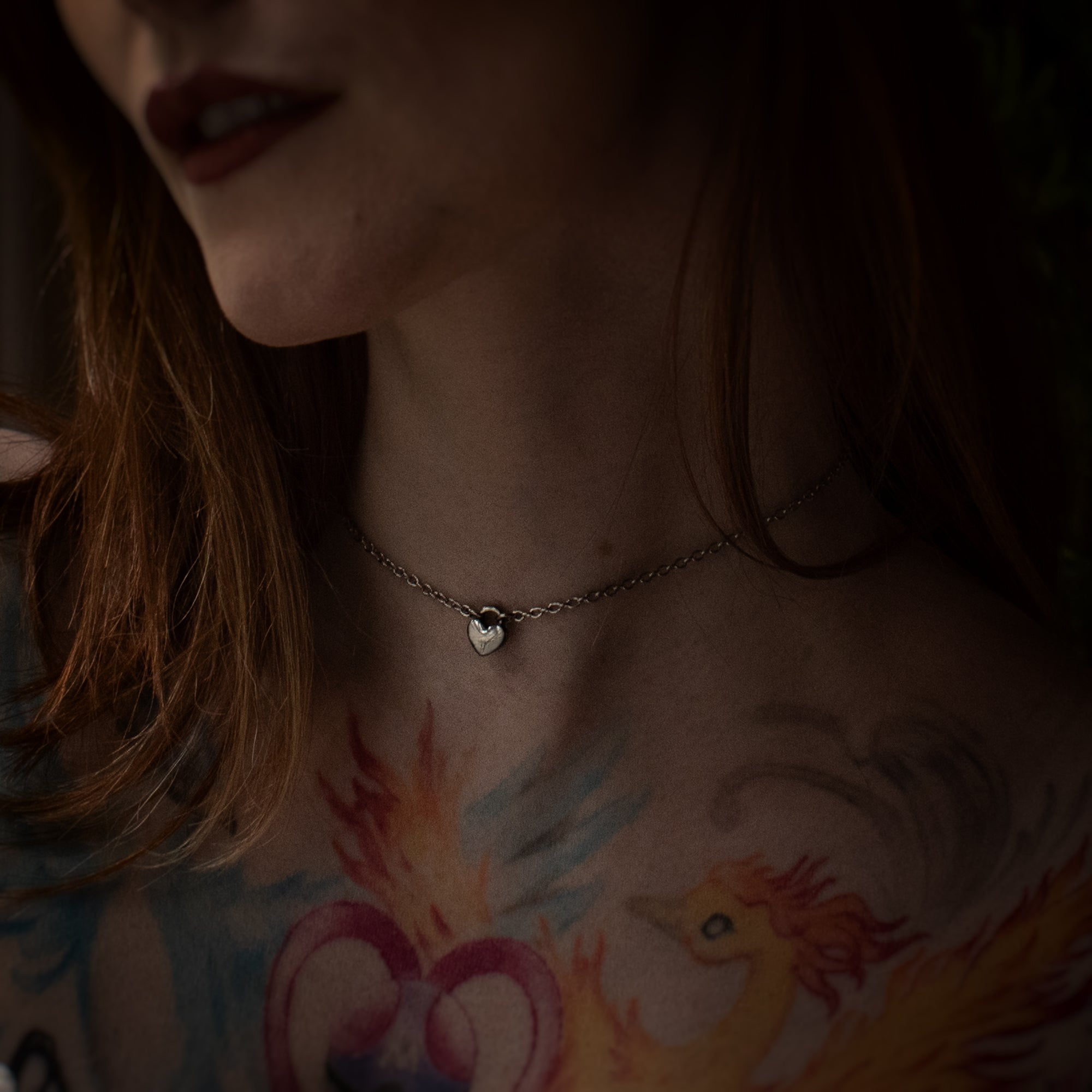 Tiny silver coloured heart pendant day collar on a dainty cable style chain, worn by model