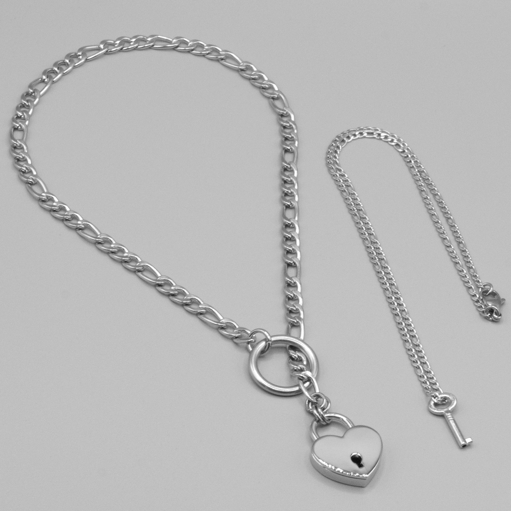 Close up of a silver coloured figaro style slip chain choker with a heart shaped padlock