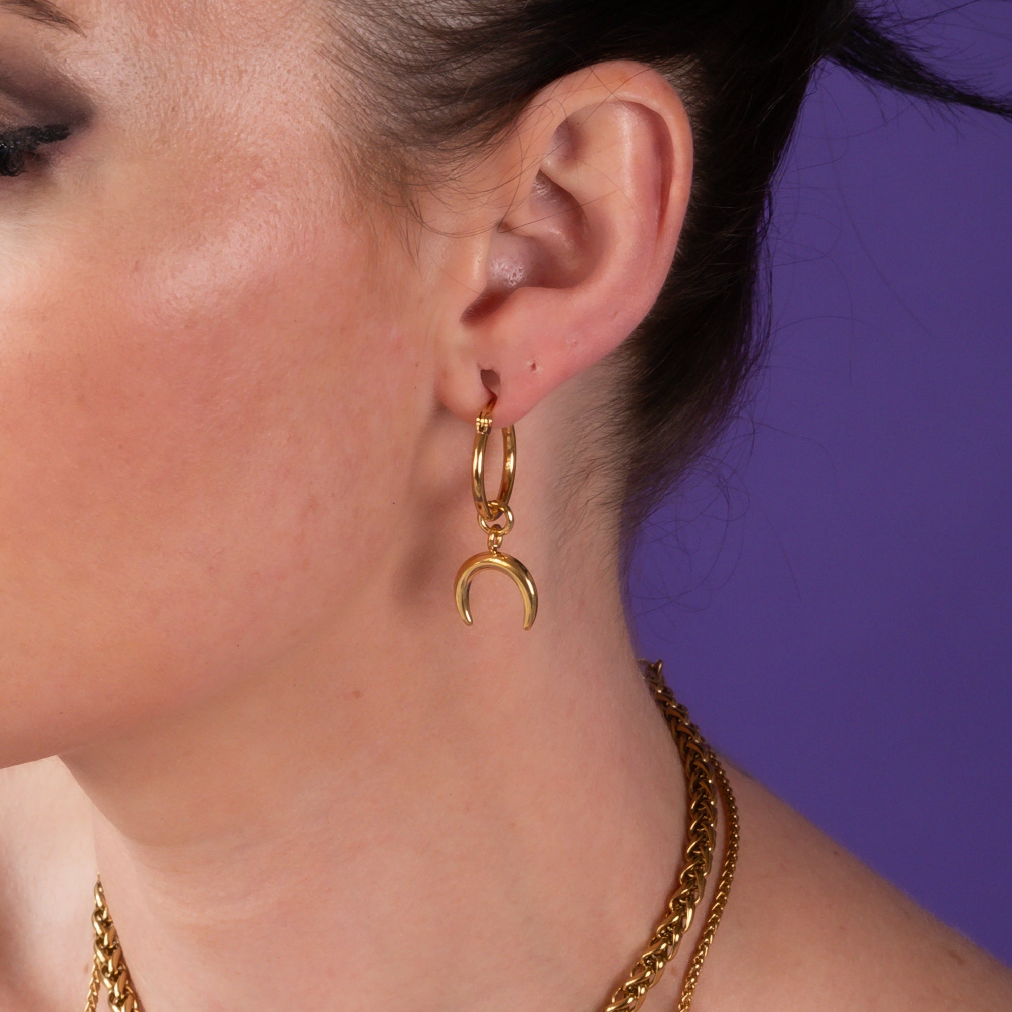 Woman with tattoos wearing gold crescent moon earrings