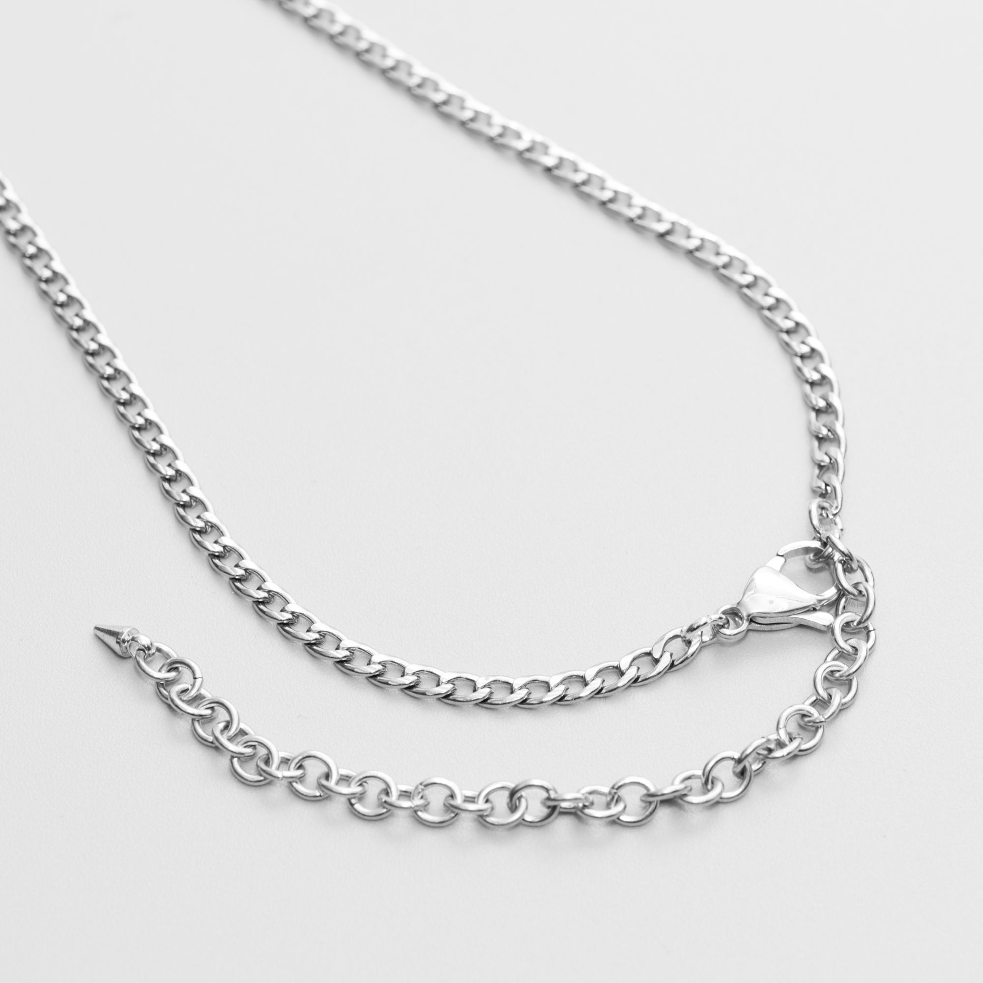 A silver-colored heart pendant micro slip chain necklace with a cuban link chain, presented on a black gift box