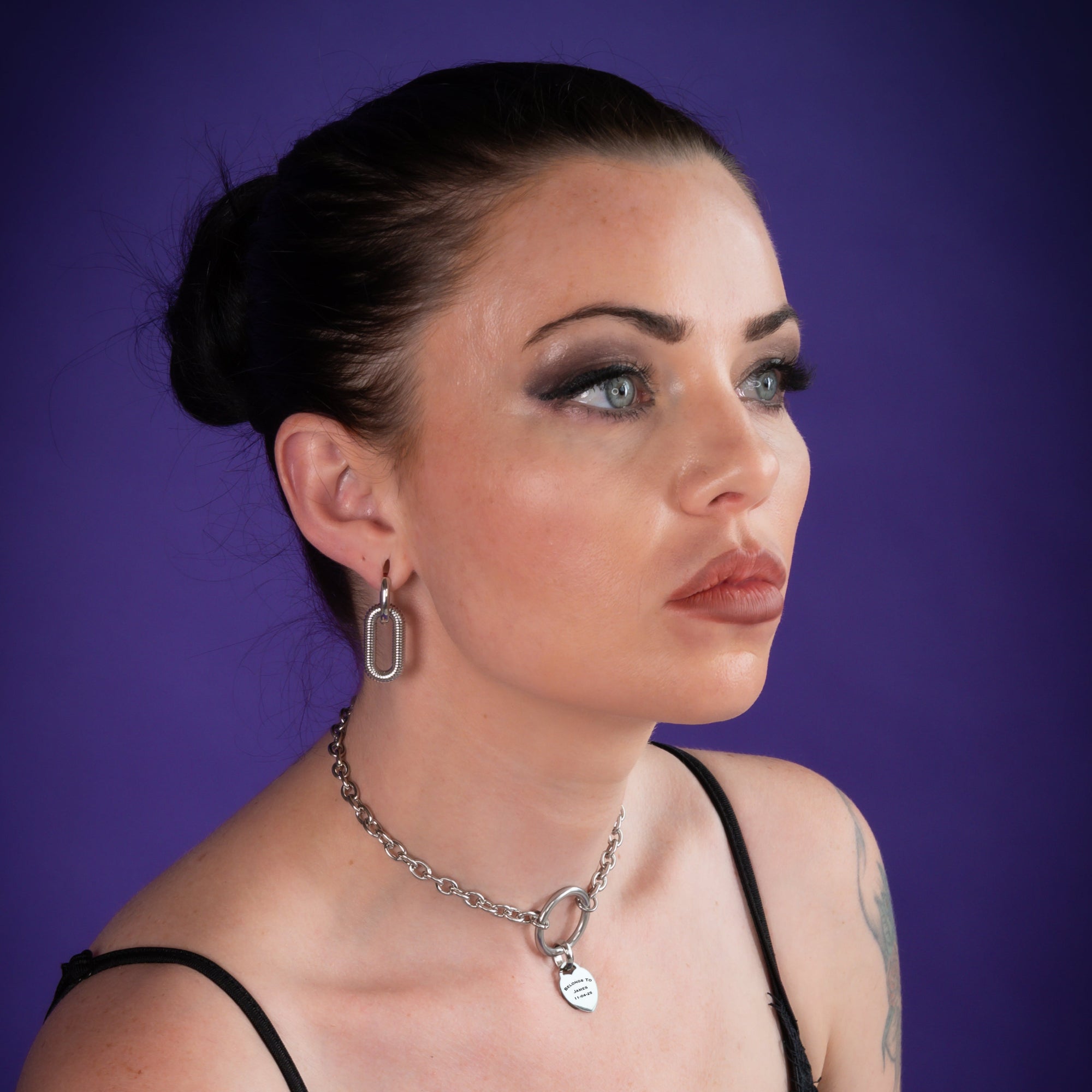 Woman wears a medium sized silver o ring choker featuring a small engraved heart pendant 