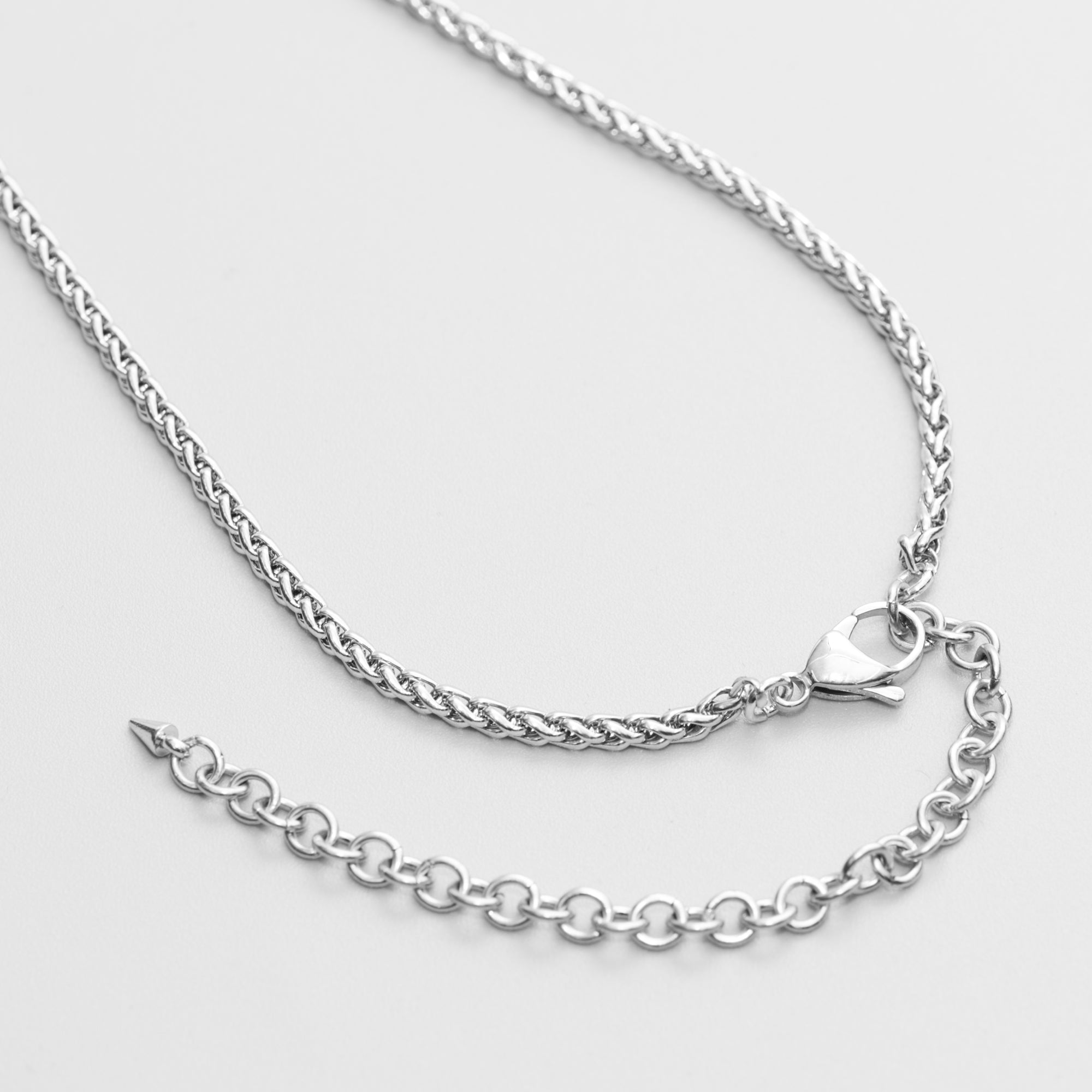 A silver heart pendant micro slip chain necklace with a Foxtail chain and a lobster clasp closure, presented on a black gift box 