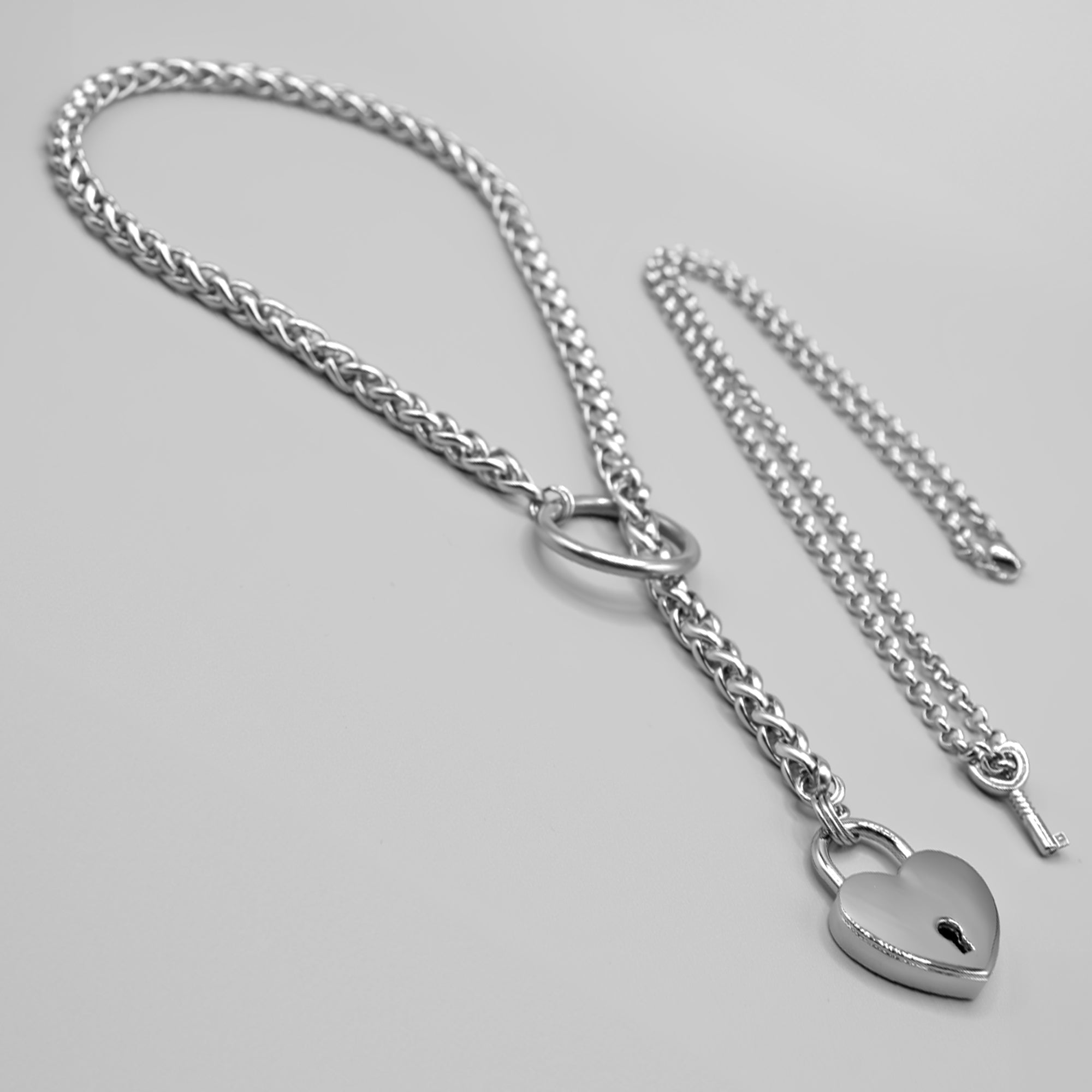 A silver coloured chunky foxtail style slip chain choker with heart padlock & key on belcher necklace, also known as a padlock choker