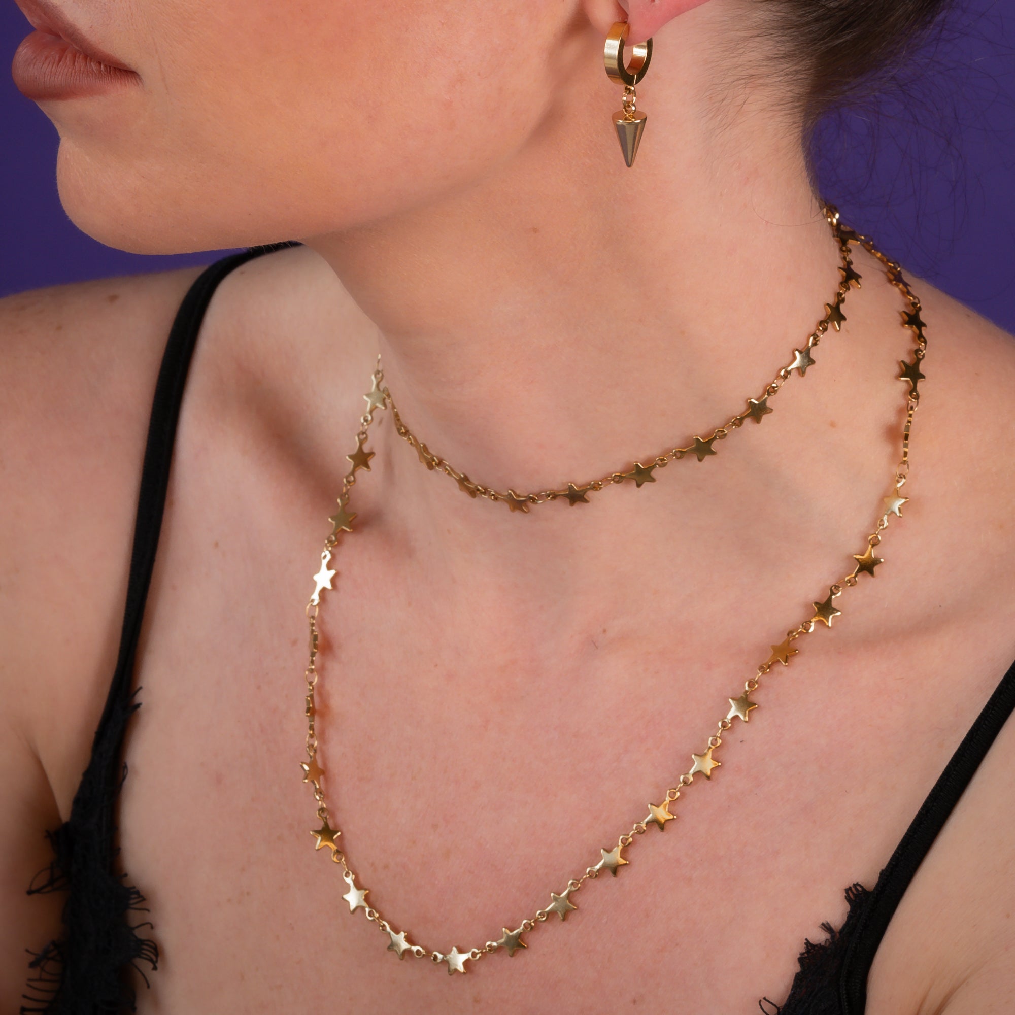 Woman wearing a Gold star link choker necklace with matching earrings 