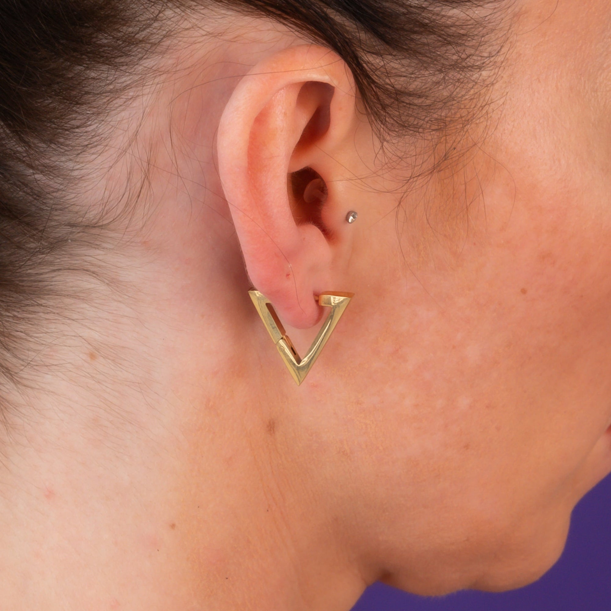 Woman wearing gold triangle earrings with chunky gold cuban necklace