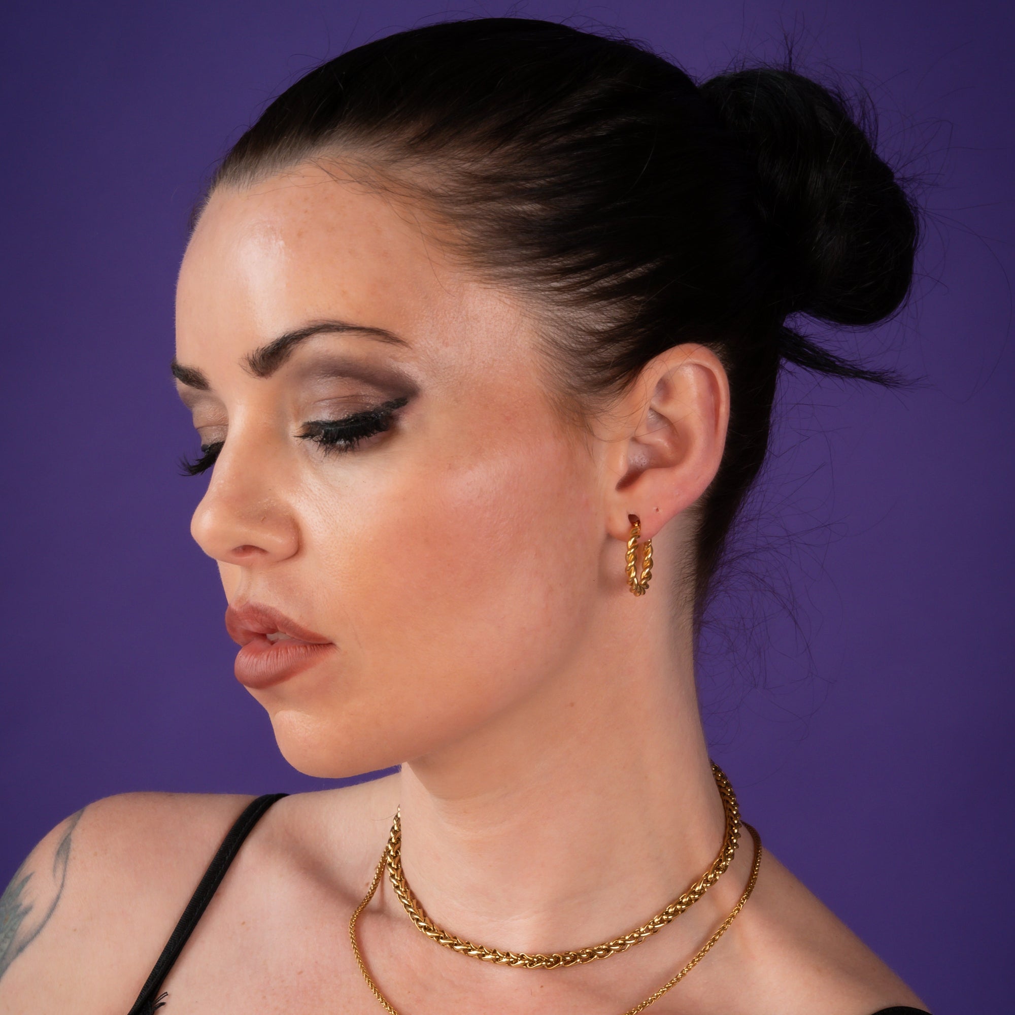 Woman wearing large twisted gold hoop earrings