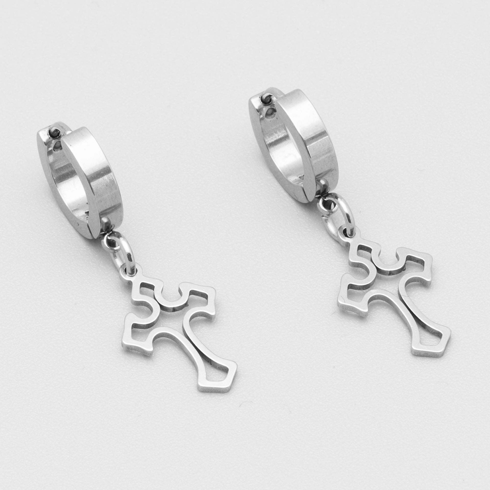 Close up of Gothic cross huggie hoop earrings in silver 