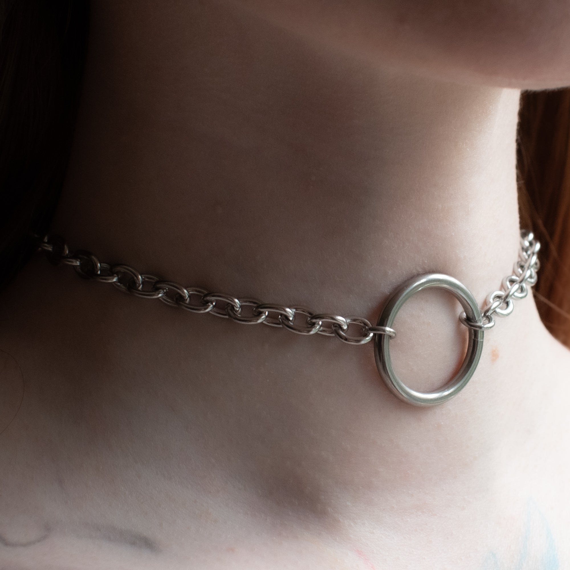 Close up of a silver coloured medium thickness O ring day collar worn by model