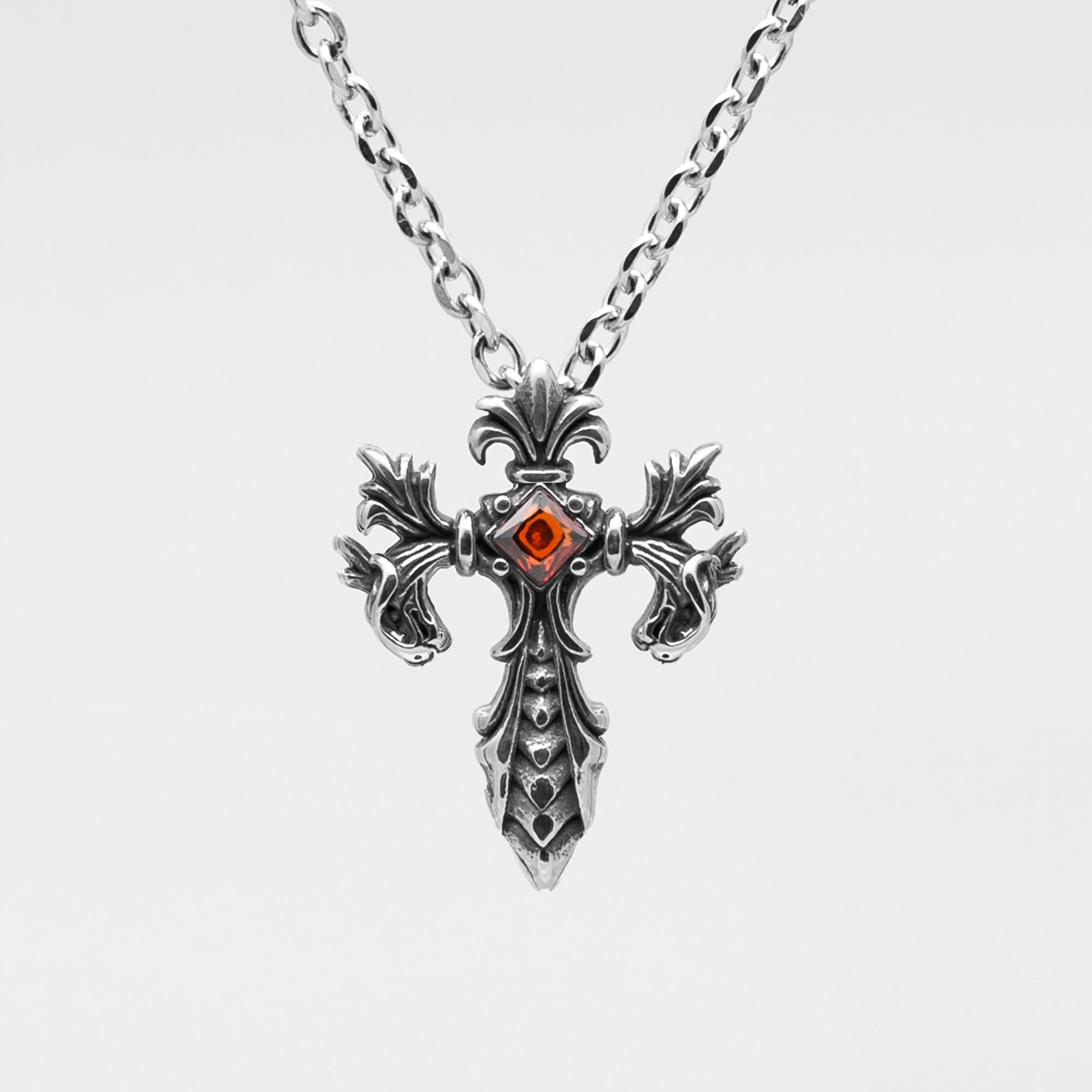 silver Gothic style cross with a single red gem stone set on a silver cable chain 